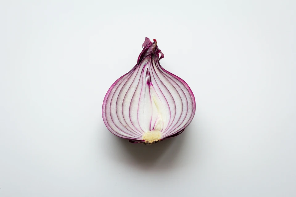 A halved red onion with purple and white layers visible.